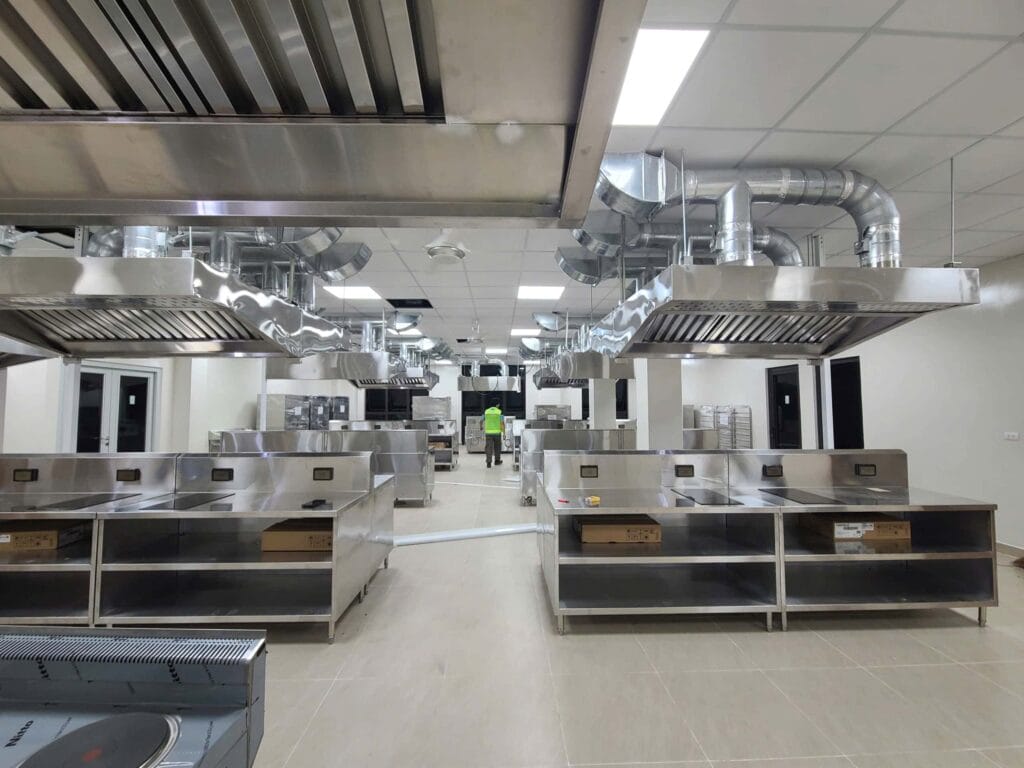 Toàn cảnh bếp ăn công nghiệp/bếp nhà hàng lớn với thiết bị và đường ống thông gió inox cao cấp trong giai đoạn hoàn thiện.